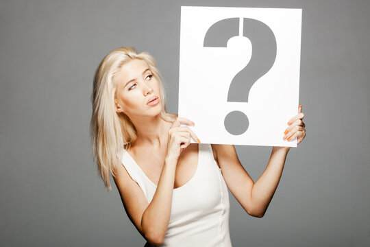 beautiful blond girl in white dress holding a question mark sign.
