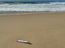 Message In A Bottle Washed Up On A Sandy Beach.
