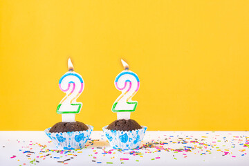 22 number candle on a cup cake with colorful sprinkles and yellow background twenty second birthday anniversary celebrations