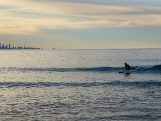 Wall Mural - A surfer crouched down riding a small wave at Snapper Rocks by himself - Australia