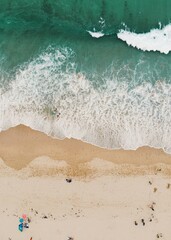 Wall Mural - Turquoise waves crashing to the golden sands shore with people on the beach