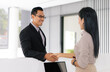 Handsome Asian businessman handshake to the receptionist the hostel reception desk. Business travel concept.