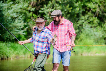 Wall Mural - funny fishing. male friendship. family bonding. two happy fisherman with fishing rod and net. father and son fishing. summer weekend. mature men fisher. hobby and sport activity. Trout bait