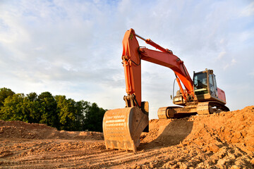 Excavator dig sand at the open-pit. Heavy machinery working in the mining quarry. Digging and excavation operations. View on the mountains with yellow sand