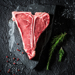 Raw and red steak with salt, pepper and rosemary