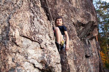 cute teen kid climbing on rock with insurance, lifestyle sport people concept