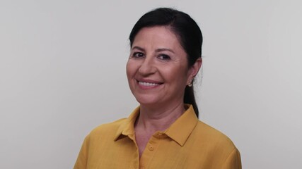 Wall Mural - Smiling beautiful old woman in her 55s isolated on white background in studio.Camera charming smile, wink.