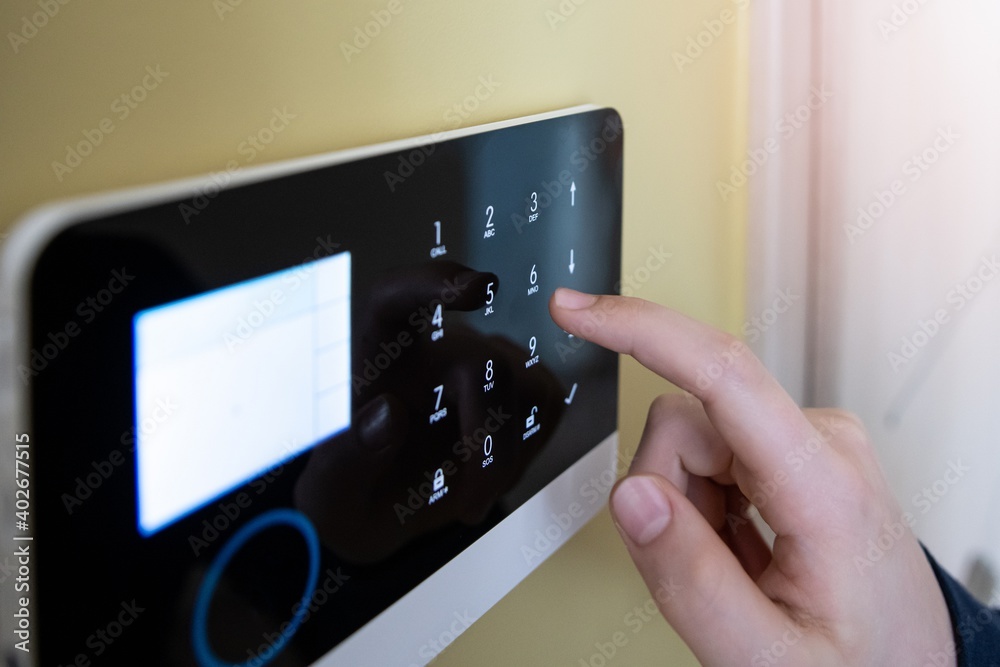 Man's hand pressing the alarm system button. Home security. - obrazy, fototapety, plakaty 