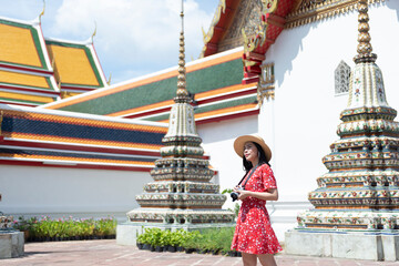 Wall Mural - Asian Girl Tourist is visiting Wat Pho or the Reclining Buddha Temple, one of the most-visited attraction in Bangkok, Thailand.