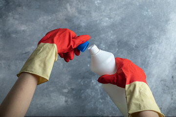 Wall Mural - Hands in red gloves opening container of bleach