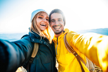 Wall Mural - Couple hiking mountains - Happy friends with backpack taking a selfie climbing hills