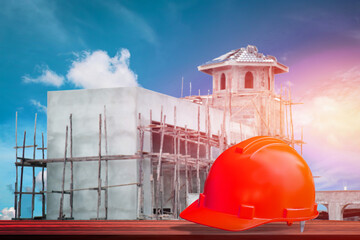 Safety hard helmet Orange color front side view on wooden and front village construction  project site background, fore safety concept.