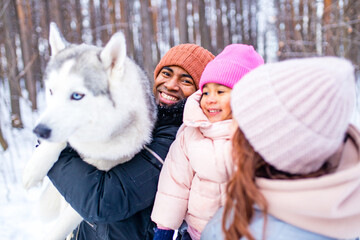 Wall Mural - mixed race family in threesome spending new year holidays in park with their husky dog