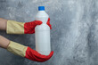 Hands in red gloves holding container of bleach