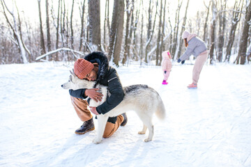 Wall Mural - mixed race man hug his dog husky in winter forest park