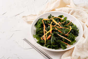 Wall Mural - homemade seaweed salad or kelp in a white dish on white table background