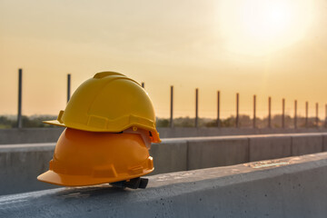 Wall Mural - Two Yellow hard safety helmet hat for dafety project of workman as engineer or worker, on concrete in construction site during build a bridge over the road.