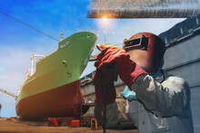 Ship Repair Industry Welding Worker With Spark Light Wear Equipment Protective On Tanker Ship Moored In Floating Dry Dock Background In Shipyard.