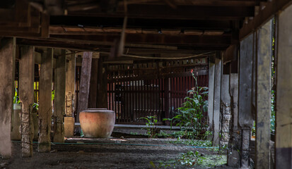 Wall Mural - Old big earthen jar or Large vintage clay jar for water storage on the ground under the thai ancient style house. No focus, specifically.