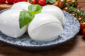 Wall Mural - Cheese collection, white balls of soft Italian cheese mozzarella, served with red cherry tomatoes, fresh basil leaves