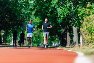 Two healthy young men running in the park on a sunny day..