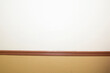 © Brandy McKnight - Blank white and tan wall separated by brown moulding
