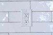 Three slot grounded receptacle for appliances against white tile wall of home