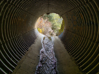Water flowing through large metal drainage pipe 