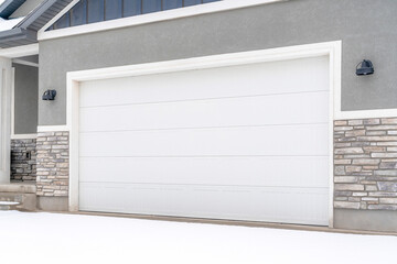 Wall Mural - Wide white garage door of home with gray exterior wall on a snowy winter day