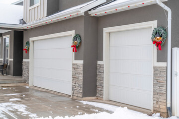 Wall Mural - White garage doors of home with festive wreaths mounted on the gray wall