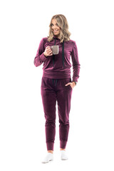 Wall Mural - Happy confident young casual woman in leisure wear holding coffee or tea mug smiling at camera. Full body length isolated on white background.