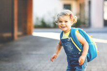 Cute Little Adorable Toddler Girl On Her First Day Going To Playschool. Healthy Beautiful Baby Walking To Nursery School And Kindergarten. Happy Child With Backpack On The City Street, Outdoors.
