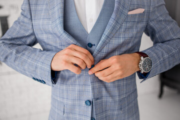 Poster - a man buttons up the buttons of a blue suit jacket