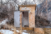 Old Abandoned Public Restroom In The Mountain Surrounded By Leafless Brown Trees
