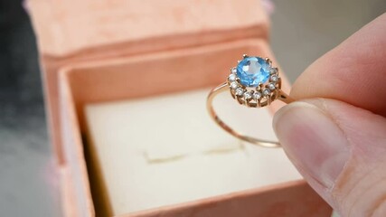 Wall Mural - beautiful golden ring with blue topaz and diamonds in hand near present box