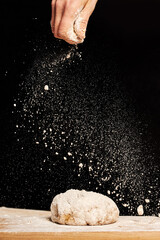 Female baker hands making dough for bread with an apron. Natural homemade ingredients. Dark background, brown color grading.