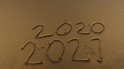 Wall Mural - message year 2020 replaced by 2021 written on beach sand background. good bye 2020 hello to 2021 lap
