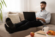 © Сергій Свиридюк - Man lying on sofa at home and working on laptop