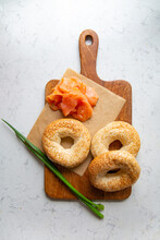 Breakfast Composition With Bagels With Sesame Seeds On A Cutting Board, On A Marble Background, Top View.