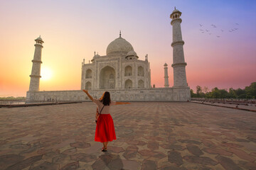 Fototapete - Taj Mahal Agra iconic monument on the banks of river Yamuna at sunrise with female tourist enjoying the view