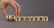 Introvert or extrovert symbol. Hand turns cubes and changes the word 'introvert' to 'extrovert'. Beautiful grey background, copy space. Psychological and Introvert or extrovert concept.