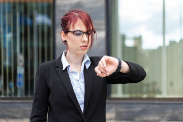 Confident young female manager outdoor checking the time on her watch