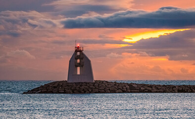 Wall Mural - Panorama d'un coucher de soleil sur une digue avec vue sur le phare de La Grande Motte, sud de la France près de la Camargue.	