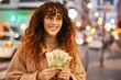 Young hispanic woman smiling happy holding israel shekels banknotes at the city