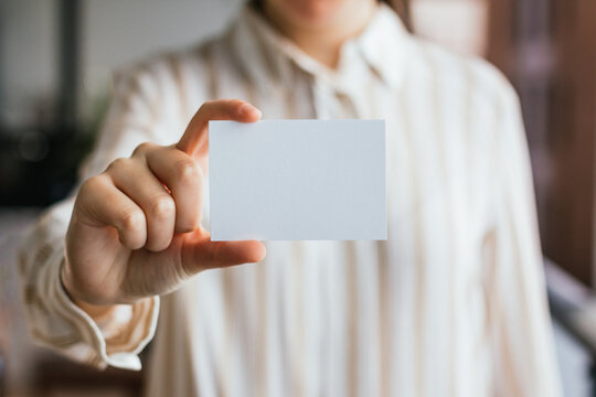 Blank paper business card mockup held by a woman's hand. Branding design template concept