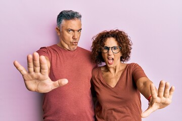 Sticker - Beautiful middle age couple together wearing casual clothes doing stop gesture with hands palms, angry and frustration expression