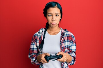 Poster - Beautiful hispanic woman playing video game holding controller depressed and worry for distress, crying angry and afraid. sad expression.