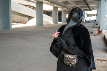 Wall Mural - plague doctor in an empty city on an empty marina holds a flower