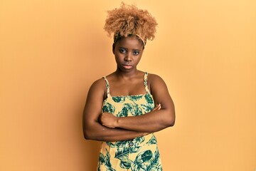 Poster - Young african woman with afro hair wearing summer dress skeptic and nervous, disapproving expression on face with crossed arms. negative person.