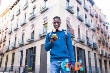 Wall Mural - African American Man Using Cellphone Holding Skateboard Outdoors.